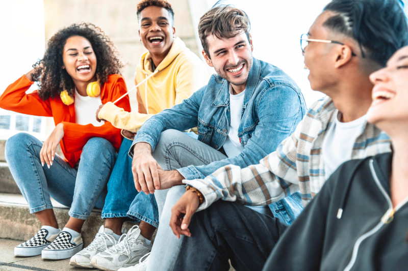 College students sitting on steps outside laughing and smiling.